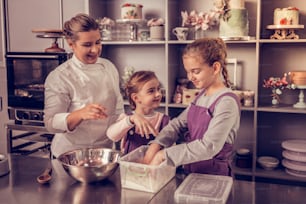 Family activity. Joyful happy girls smiling while having fun together in the kitchen