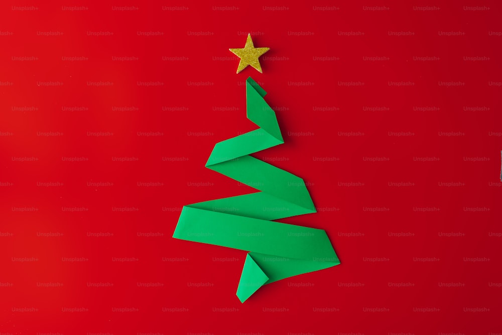 Minimal origami style folded paper christmas tree on red background.