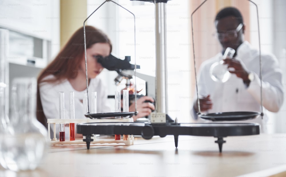 assistente de laboratório com microscópio de laboratório de vidro bulbo com produtos químicos