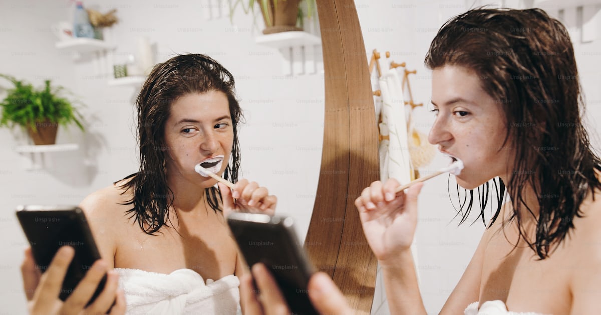 Social media affect. Young happy woman in white towel brushing teeth ...