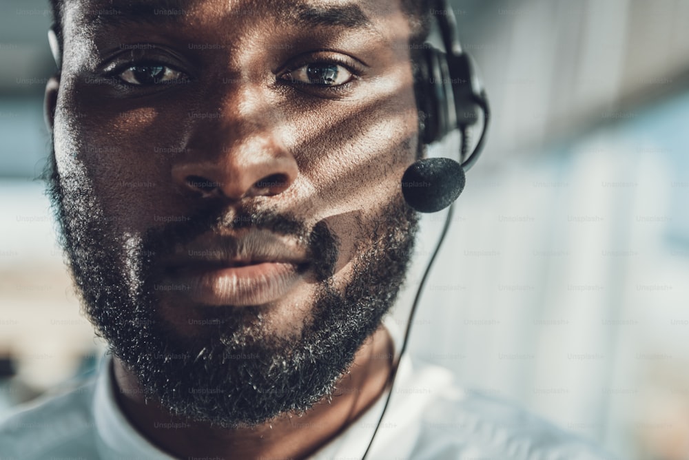 Call center supporting office. Front view portrait of afro-american male specialist in headset looking straight on camera