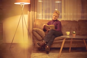 Garder son esprit actif et engagé. Femme âgée lisant un livre à la maison.