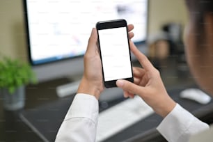 Mockup smartphone on female hands empty display on office table with blur background. - Image