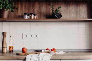 Cooking food on modern kitchen with furniture in grey color and wooden tabletop.  Knife on wooden cutting board with vegetables, pepper, spices,oil. Home food. Stylish kitchen