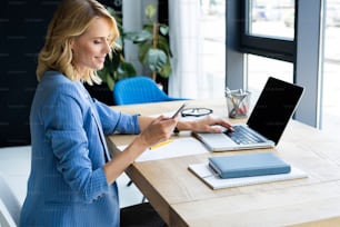 Portrait d’une femme d’affaires sérieuse utilisant un ordinateur portable dans un bureau moderne et lumineux
