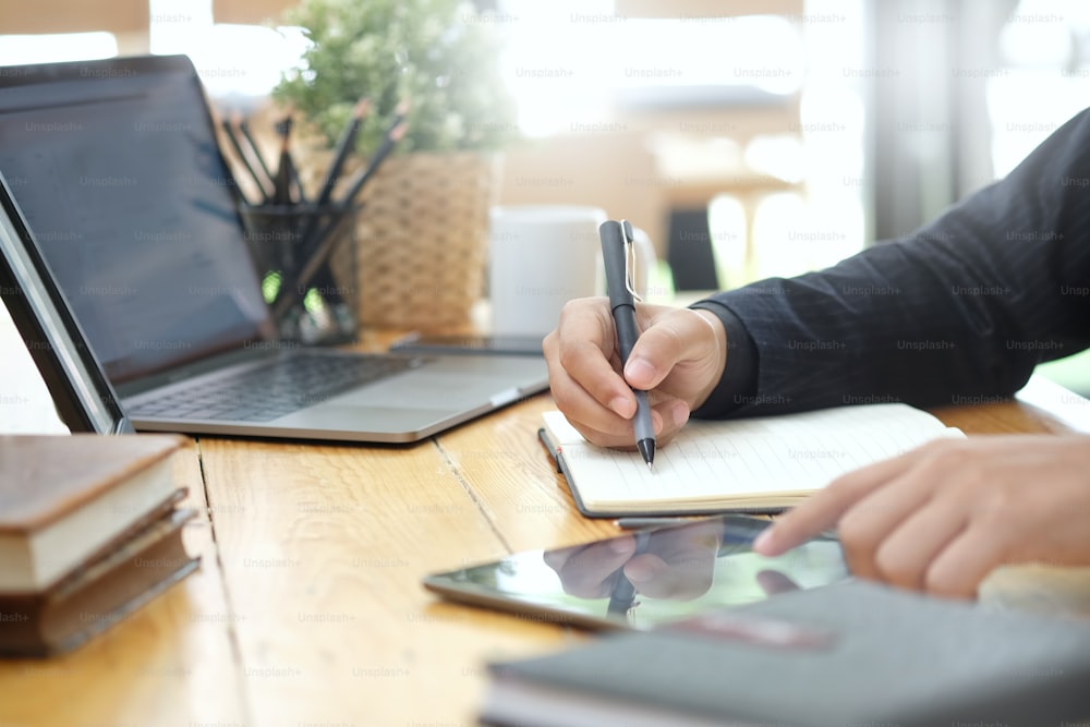Imagem recortada da mão do empresário escrevendo notas na mesa do escritório