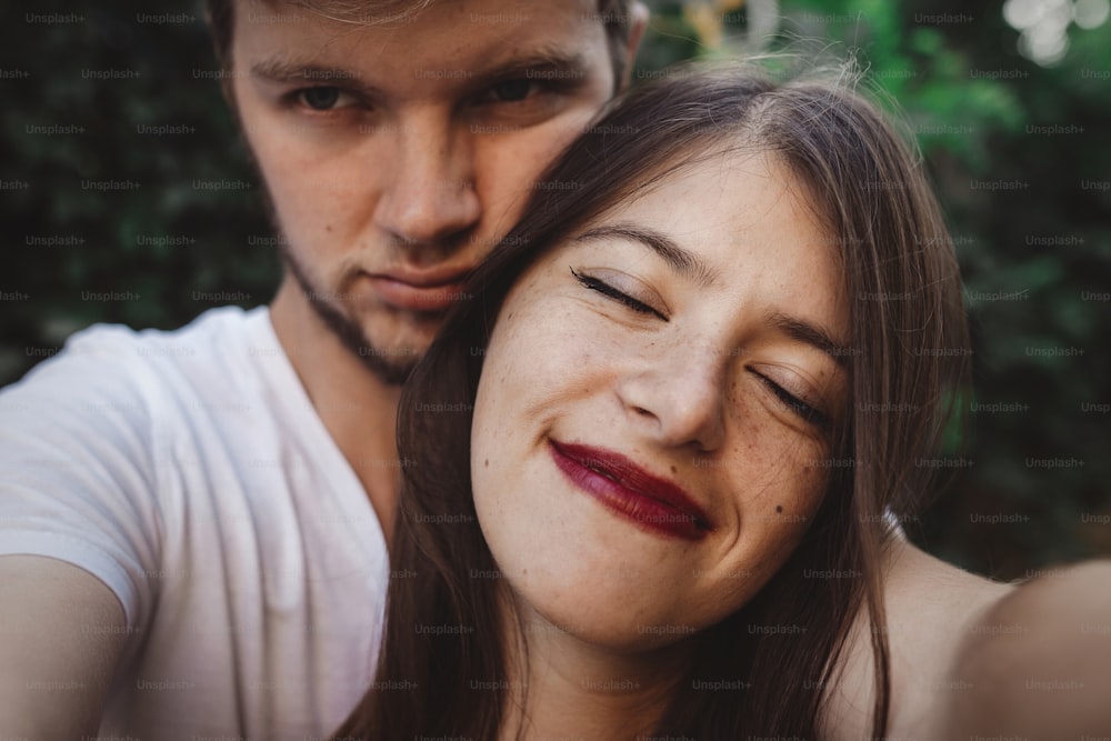 Stylish hipster couple making selfie and embracing. Happy family couple in love making self portrait and smiling in evening summer city. Vacation  and travel together