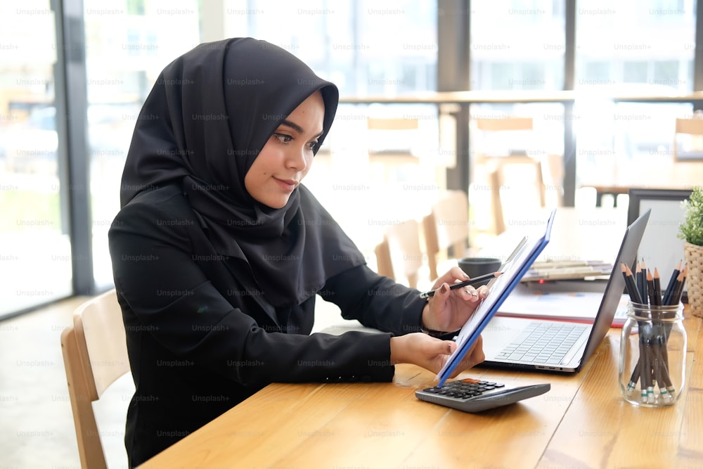 Islam Empresária que trabalha com papel de documento de finanças em mesa de madeira.