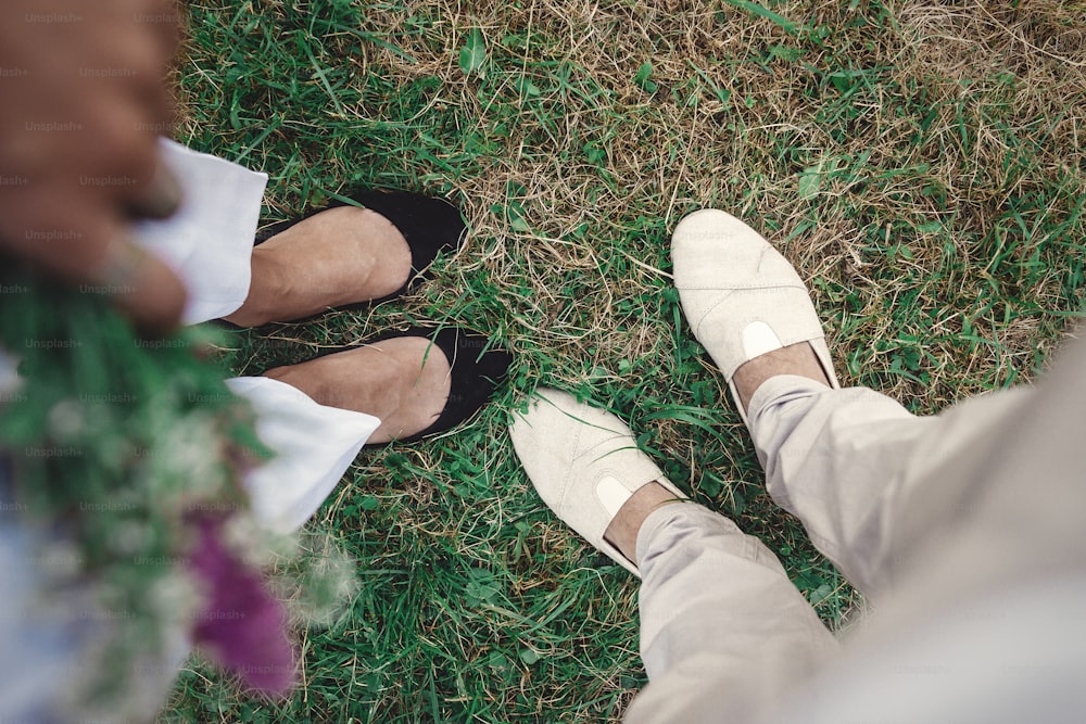 Vista superior das pernas do casal hipster elegante em sapatos. Casal familiar feliz relaxando na cidade de verão à noite. Férias e viagens juntos