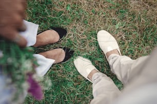 Draufsicht auf stylische Hipster-Paarbeine in Schuhen. Glückliches Familienpaar, das sich in der abendlichen Sommerstadt entspannt. Gemeinsam Urlaub und Reisen