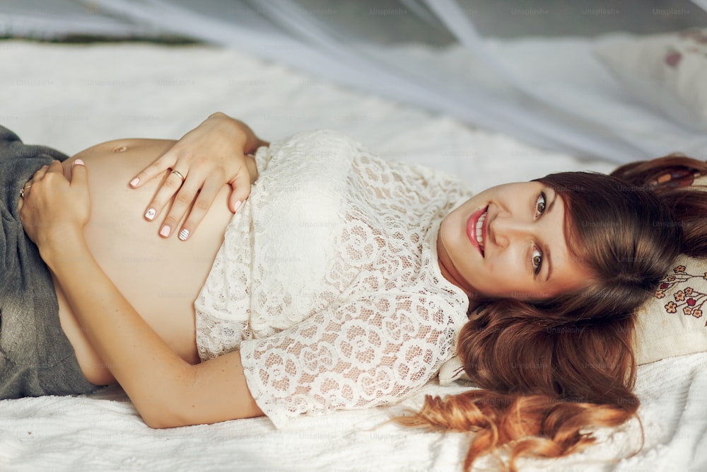 Hermosa mujer embarazada posando en un parque soleado, sosteniendo su vientre, esperando el parto. Suave y dulce momento del concepto de paternidad futura