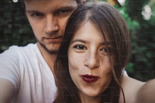 Stylish hipster couple making selfie and embracing. Happy family couple in love making self portrait and smiling in evening summer city. Vacation  and travel together
