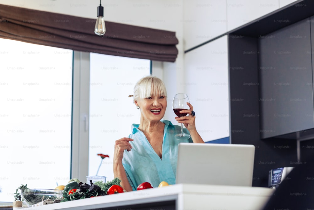 Great time. Delighted positive woman drinking wine while having a perfect day off