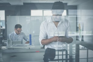 African business man standing in office. Business man reading on smart phone.