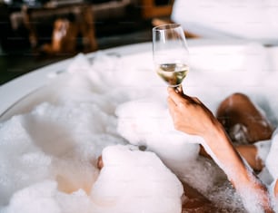 Happy black young woman relaxing in the hot tub covered in foam