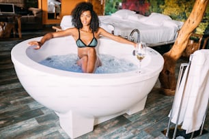 Mulher jovem negra feliz que relaxa na banheira de hidromassagem