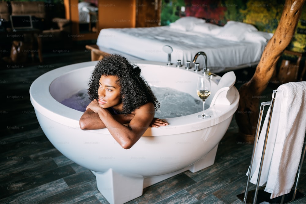 Joven negra feliz relajándose en la bañera de hidromasaje