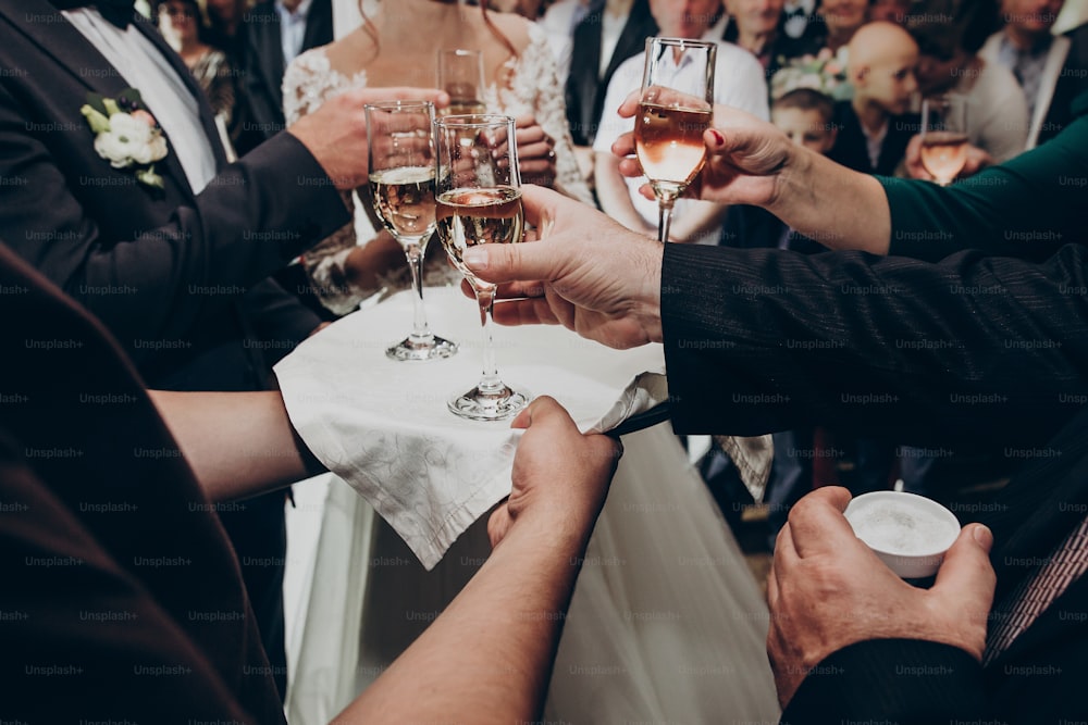샴페인 잔을 들고 있는 손. 세련 된 행복한 결혼식 커플은 가족과 함께 건배하고 결혼식을 축하합니다. 텍스트 공간. 호화로운 생활과 결혼식 피로연. 비싼 케이터링