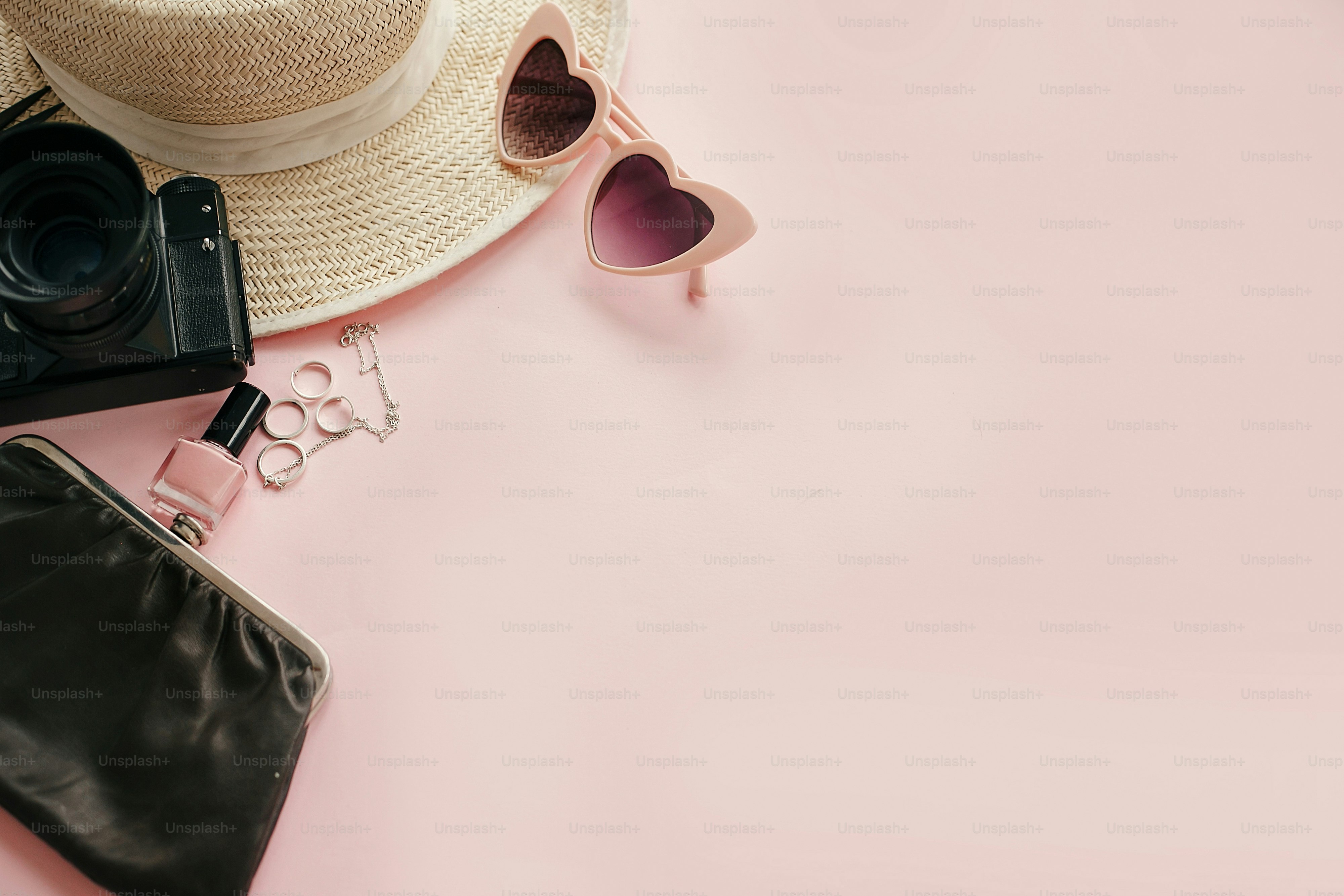 Gambar feminin bergaya dengan kamera foto, kacamata hitam merah muda retro, perhiasan, cat kuku, topi di atas kertas merah muda pastel dengan ruang salinan. Hari Perempuan Internasional. Halo konsep musim semi. Liburan musim panas