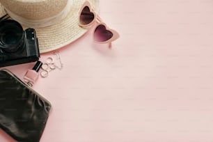 Stilvolles mädchenhaftes Bild mit Fotokamera, retro-rosa Sonnenbrille, Schmuck, Nagellack, Hut auf pastellrosa Papier mit Kopierraum. Internationaler Frauentag. Hallo Frühlingskonzept. Sommerferien