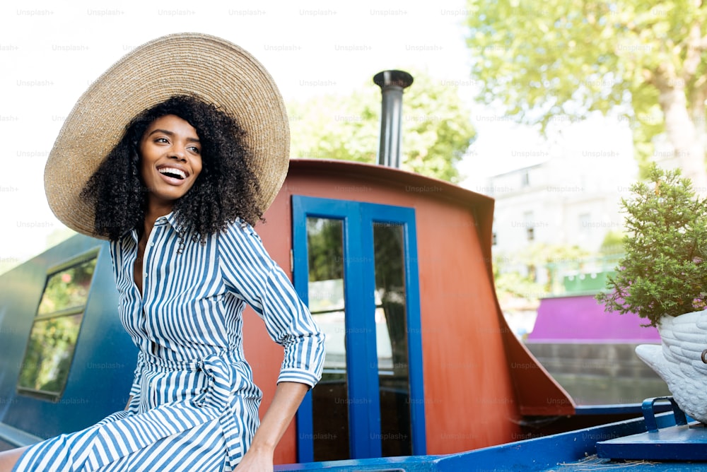 Beautiful black woman sitting in a houseboat moored in a river canal in London