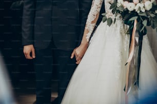 wedding couple holding hands close up at matrimony wedding ceremony in church. stylish bride and groom hugging. emotional moment, space for text. religion unity concept