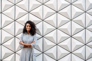 Happy pretty woman looking at camera smiling on a beautiful minimalist triangle shape wall background