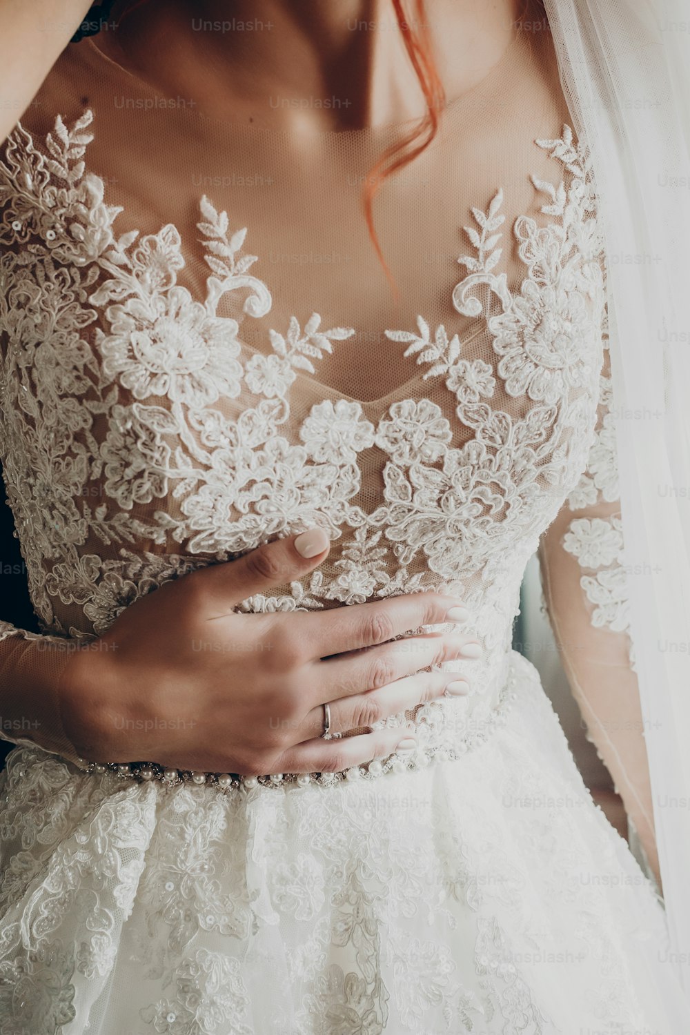 stylish happy bride hand on luxury wedding dress. amazing modern gown in sunny light at window, rustic wedding morning preparation. bridal getting ready. emotional moment. space for text