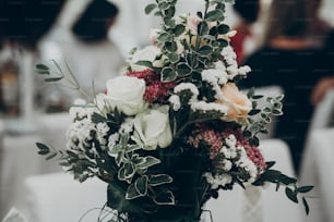 결혼식 피로연에서 테이블에 세련된 소박한 꽃다발. 텍스트 공간. 꽃꽂이와 장식. 호화로운 생활과 결혼식 피로연. 비싼 케이터링