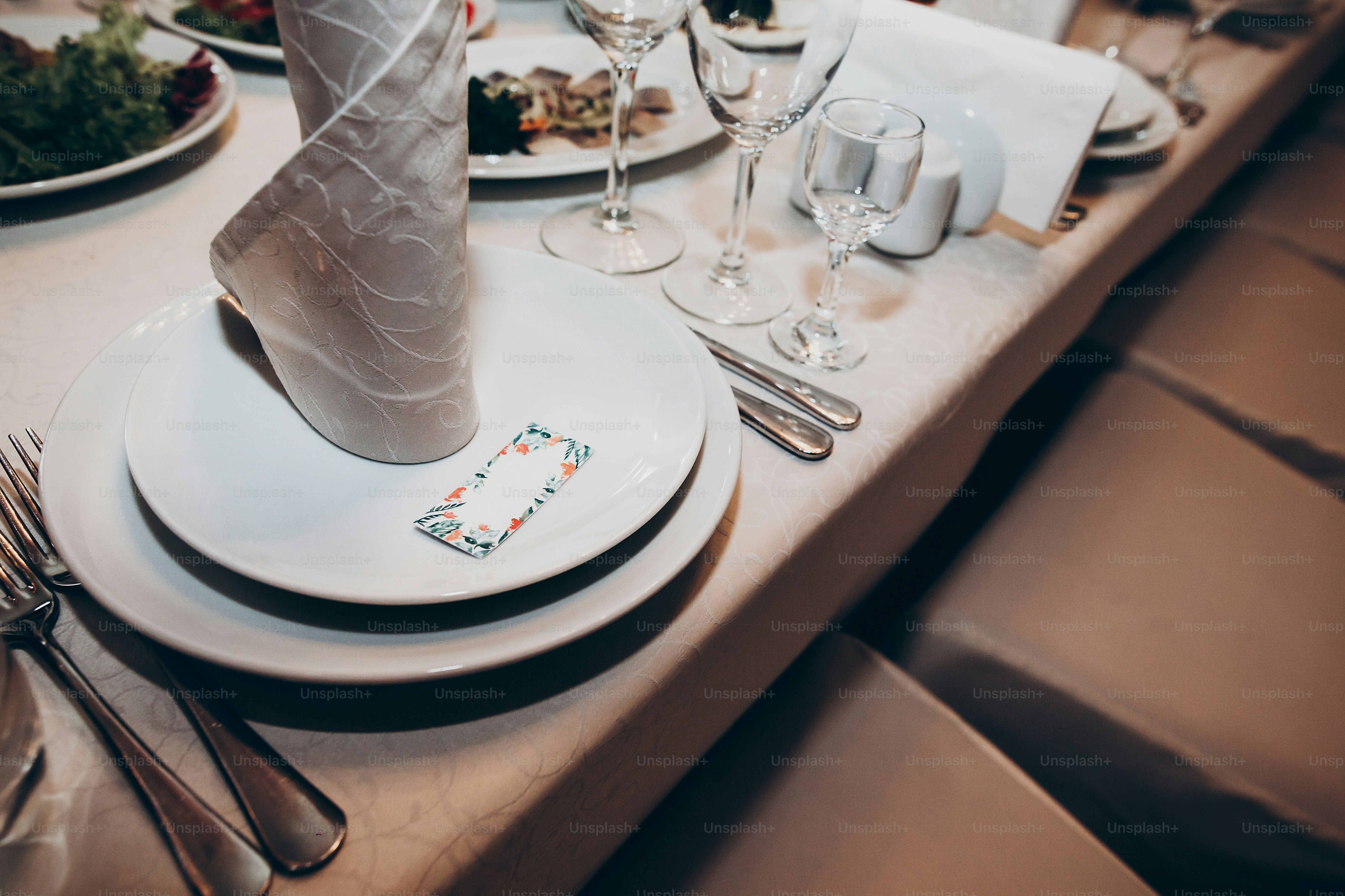Stilvolle Hochzeitskulisse. Tischgarnitur mit Einladung, Teller, Besteck, Gläsern und Serviette für luxuriöse Hochzeitsempfänge. rustikaler Strauß. Platz für Text. teures Catering