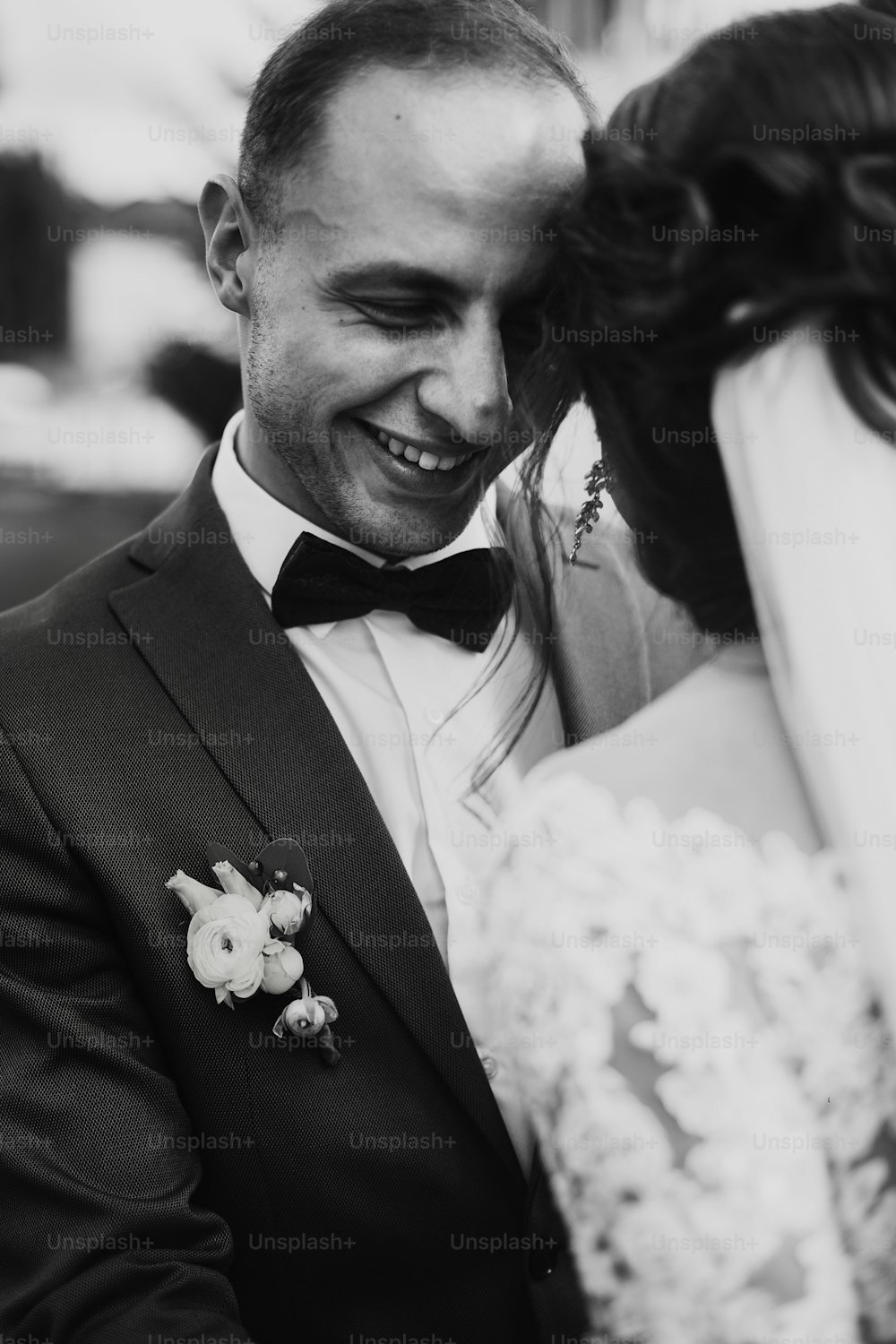 Stilvoller Bräutigam, der lächelt und seine glückliche, wunderschöne Braut umarmt und sich sanft im Park umarmt. romantischer sinnlicher Moment, Raum für Text. Luxushochzeit Brautpaar. Schwarz-Weiß-Foto