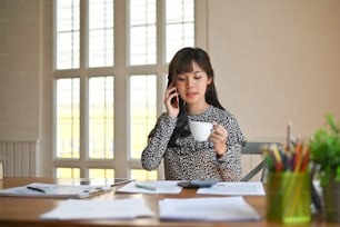Trabajo de secretaria, mujer trabajando en la mesa de la oficina y teléfono móvil de llamada con taza de café.