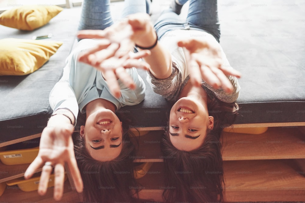 Two beautiful young twins sisters spending time together with pillows. Siblings having fun at home concept.