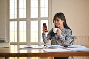 Secretary job, woman working on office table and call mobile phone with coffee cup.