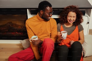 Orange polo neck. African-American man wearing orange polo neck looking at cheerful red-haired wife