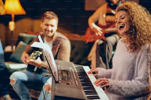 Woman playing clavier. Selective focus on woman. Home studio interior.