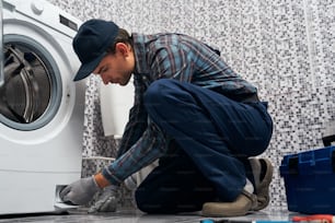 Attantive worker. Working man plumber in bathroom checking work of wacher mashine close-up