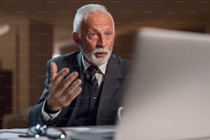Shocked mature businessman working on the computer late in the evening at his office.