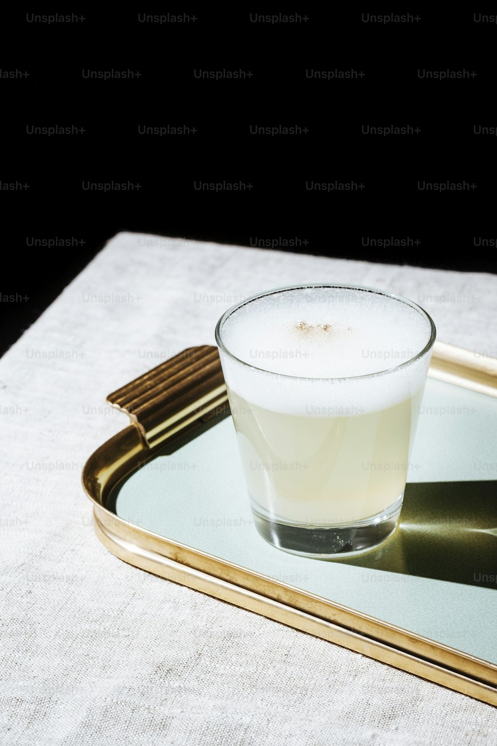 Pisco Sour, cocktail IBA with Pisco, lime or lemon juice, egg white, and angostura bitter. Dark background, pop contemporary style.