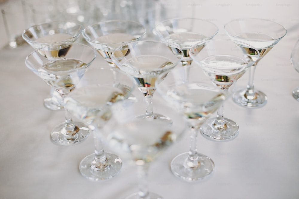 Martini row on table party at wedding reception. Martini drinks in crystal glasses at alcohol bar. Christmas and New Year feast. Celebrations and party concept.