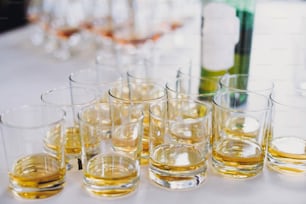 Whiskey row on table party at wedding reception. Whisky in glasses at alcohol bar. Christmas and New Year feast. Celebrations and party concept. Alcoholic drinks