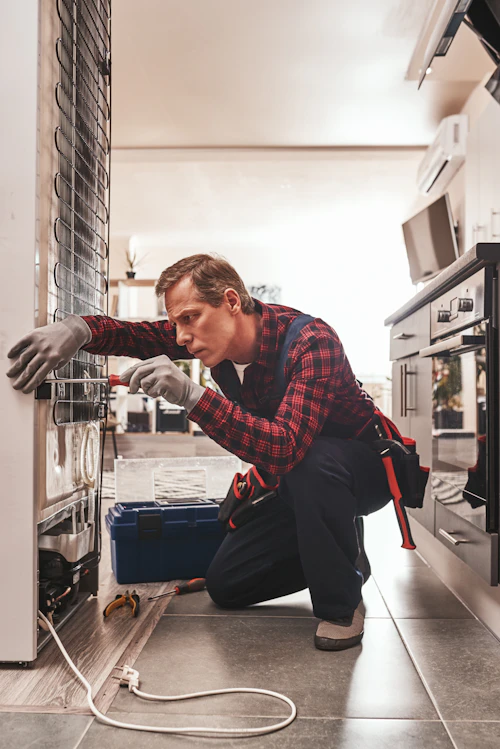 Técnico revisando la parte trasera de un refrigerador en Renca