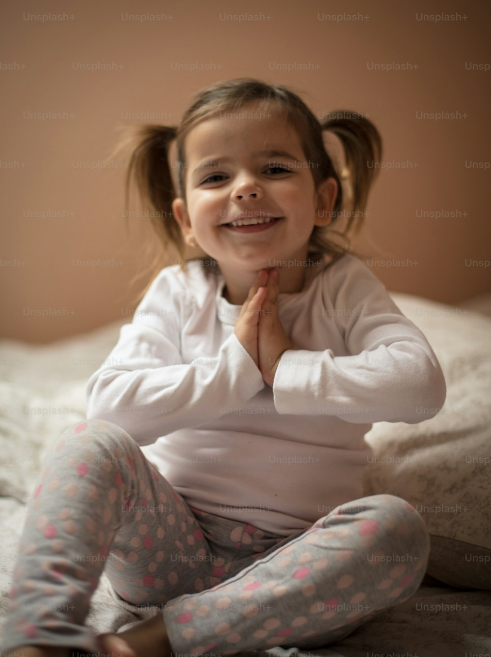 Parents learned to pray before bedtime. Little girl praying on bed. Close up.