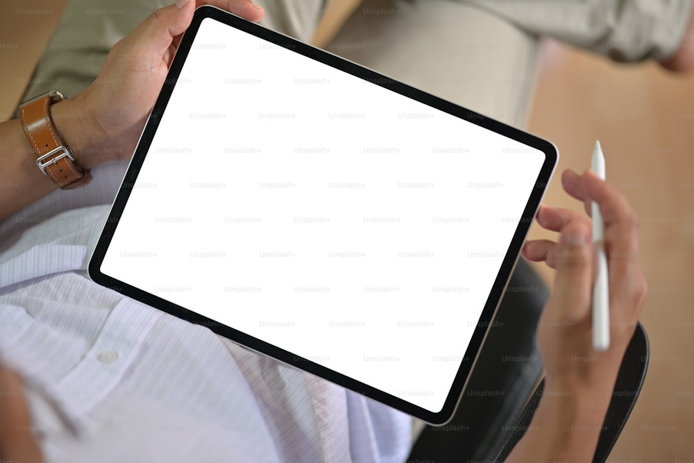 Vista superior de un hombre sosteniendo un dispositivo de tableta digital con pantalla en blanco de maqueta