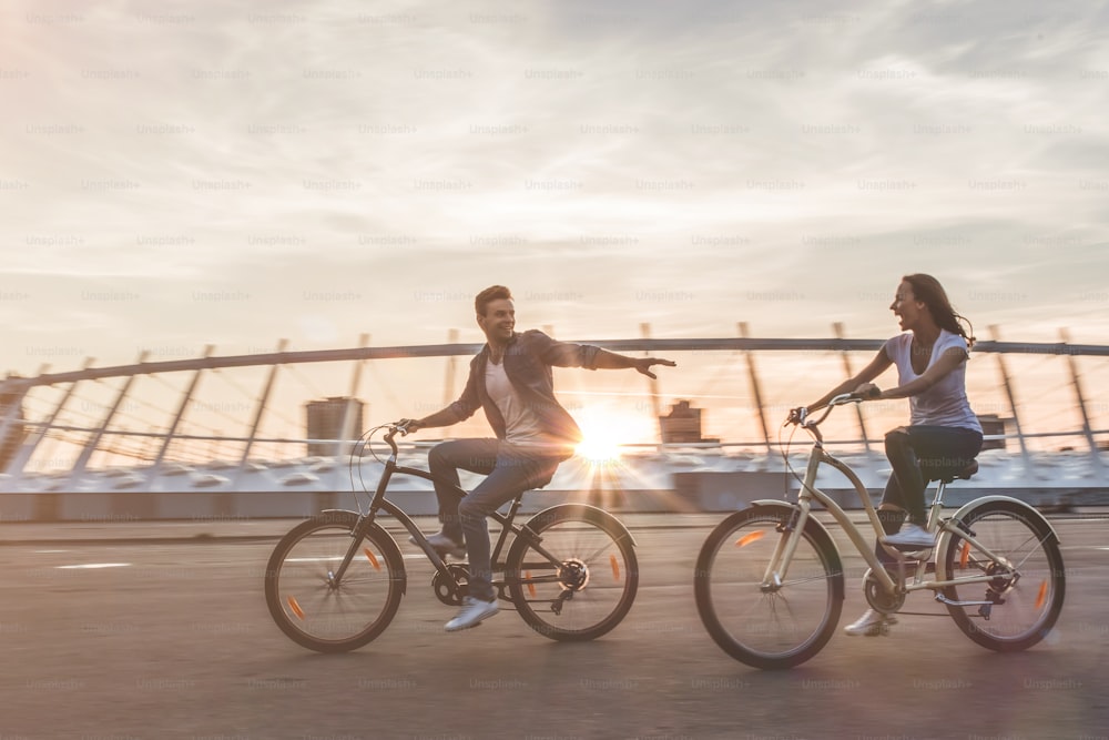 Beau couple romantique se repose dans la ville avec des vélos au coucher du soleil. Profiter de la compagnie de l’autre.
