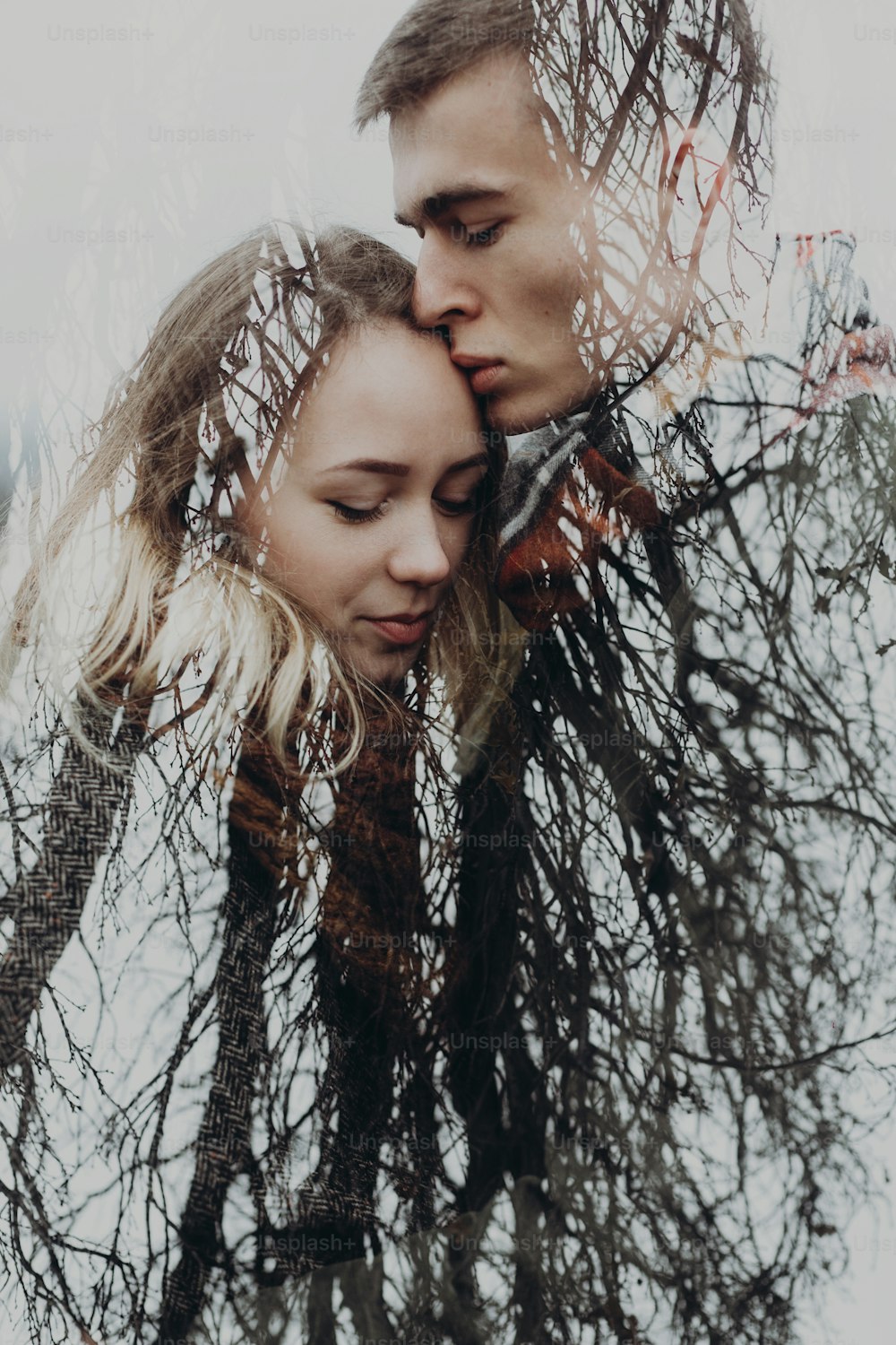 秋の公園でカップルと木の枝で二重露光。スタイリッシュなヒップスターの官能的な雰囲気の瞬間とテキストのためのスペース。抱き合う男と女。クリエイティブな珍しい写真