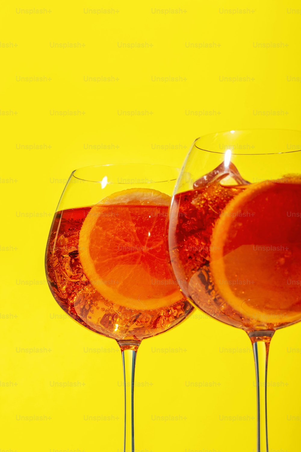 Spritz, un cocktail avec du Prosecco pétillant, de l’amer, de l’eau de Seltz et une tranche d’orange, sur fond jaune