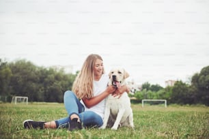 Attractive young woman with labrador outdoors. Woman on a green grass with dog labrador retriever.