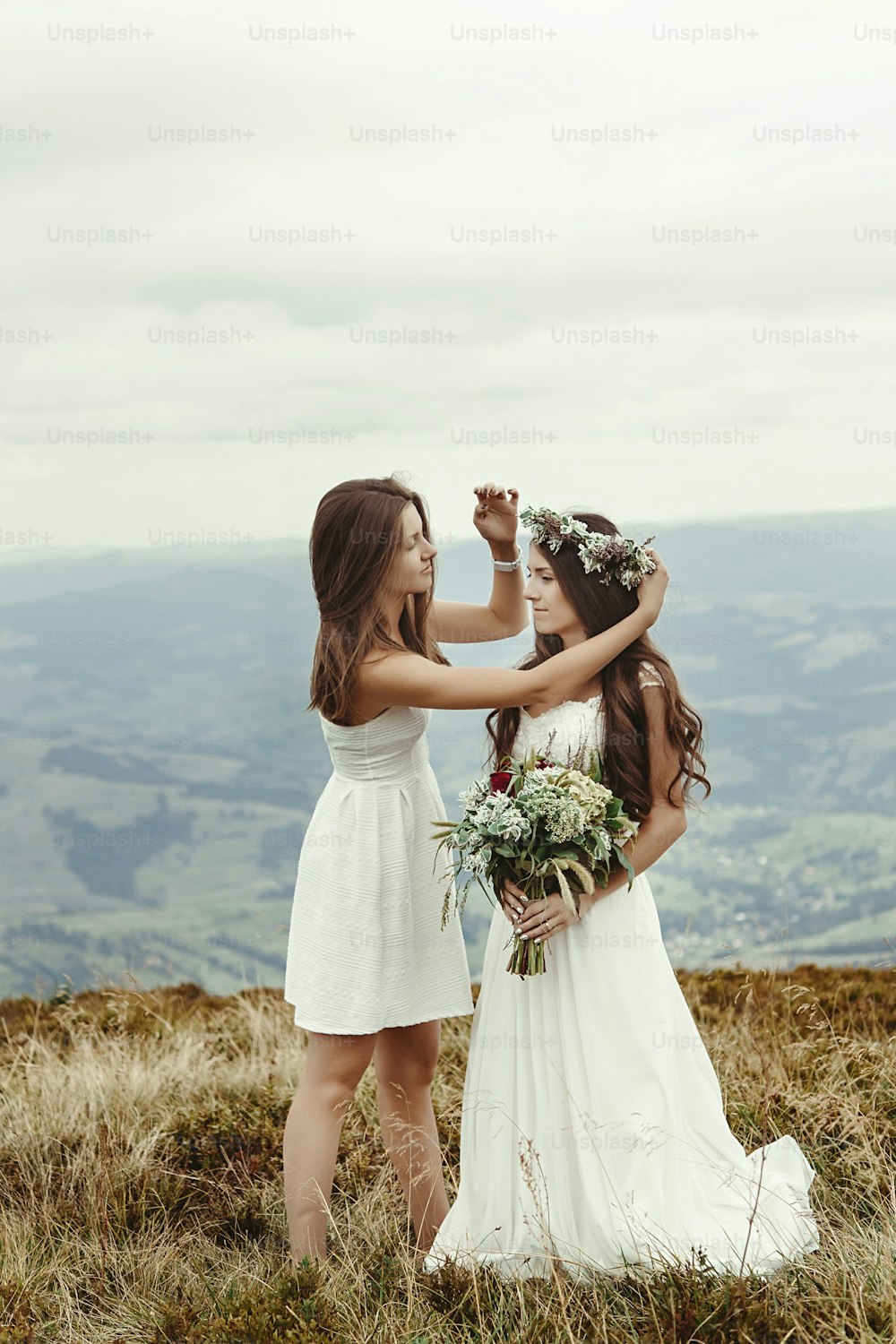 Stilvolle Brautjungfer hilft der wunderschönen Braut bei der Zubereitung, Boho-Hochzeit, Luxuszeremonie in den Bergen