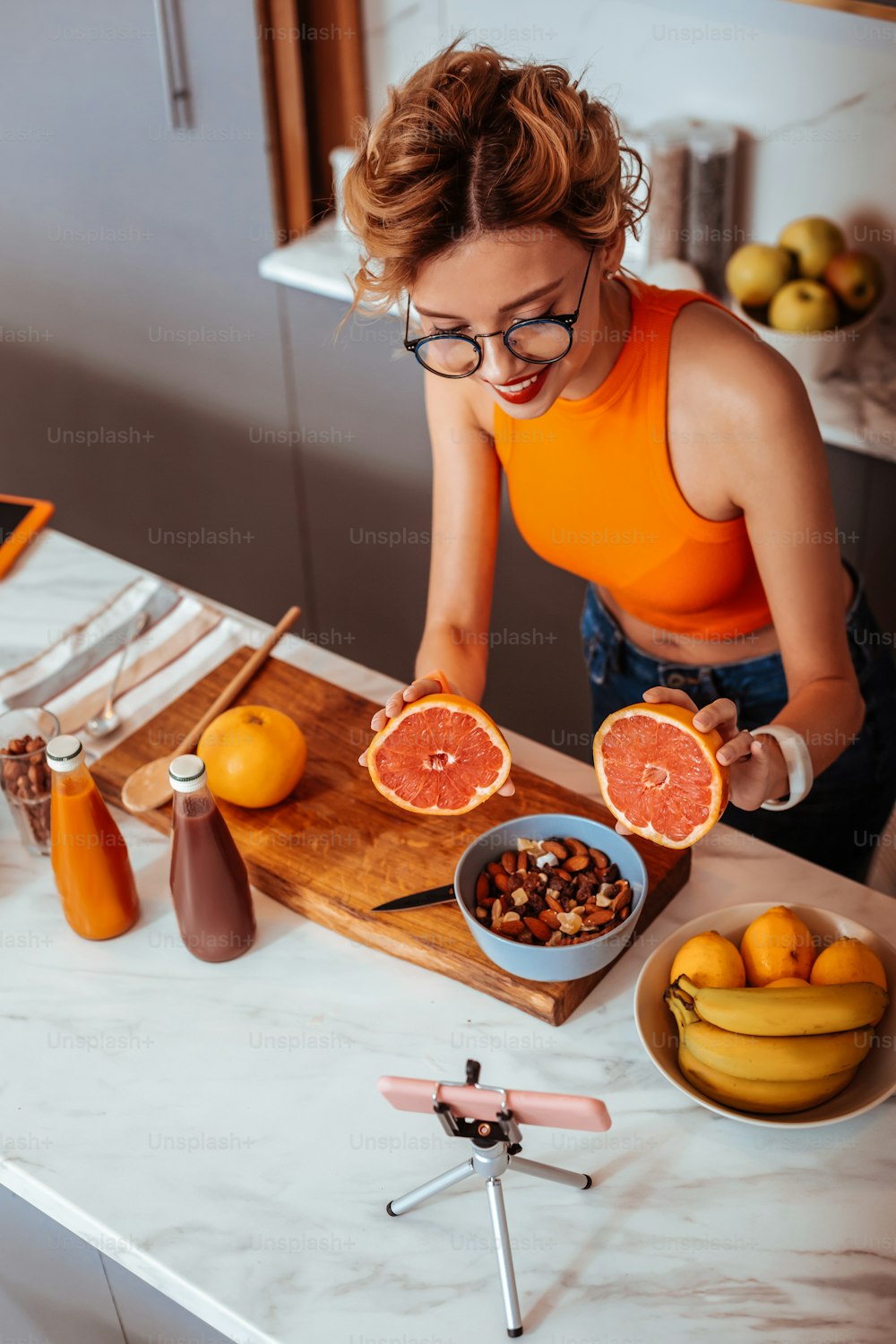 For the juice. Joyful positive woman showing two grapefruit halves while wanting to make a juice